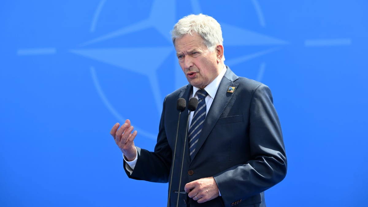 Sauli Niinistö puhuu mikrofoniin. Taustalla sininen seinä, jossa Naton logo.
