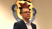 Mies taustallaan kruunuvaakuna.
