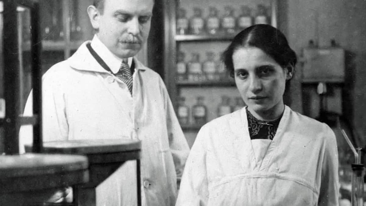 Mustavalkoinen kuva Otto Hahnista ja Lise Meitnerista valkoisissa takeissa laboratoriossa.