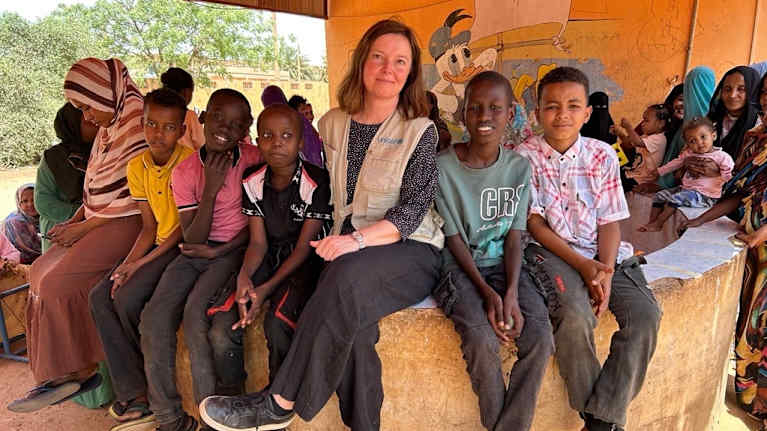 Unicef's employee sits with children.