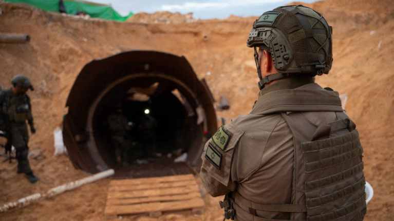 Kuvassa israelilainen sotilas seisoo selin kameraan tunnelin suun edustalla Gazassa. Taustalla näkyy kaksi muuta Israelin sotilasta. 