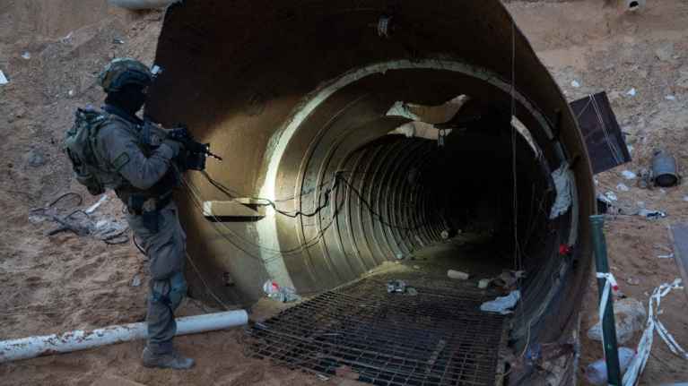 Kuvassa Israelin armeijan sotilas seisoo ase kädessään tunnelin suulla. 