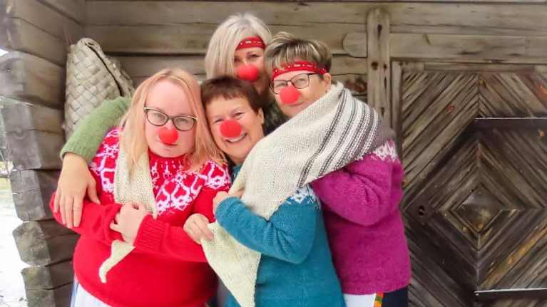 Fyra kvinnor med röda clownnäsor och en sjal runt sig.