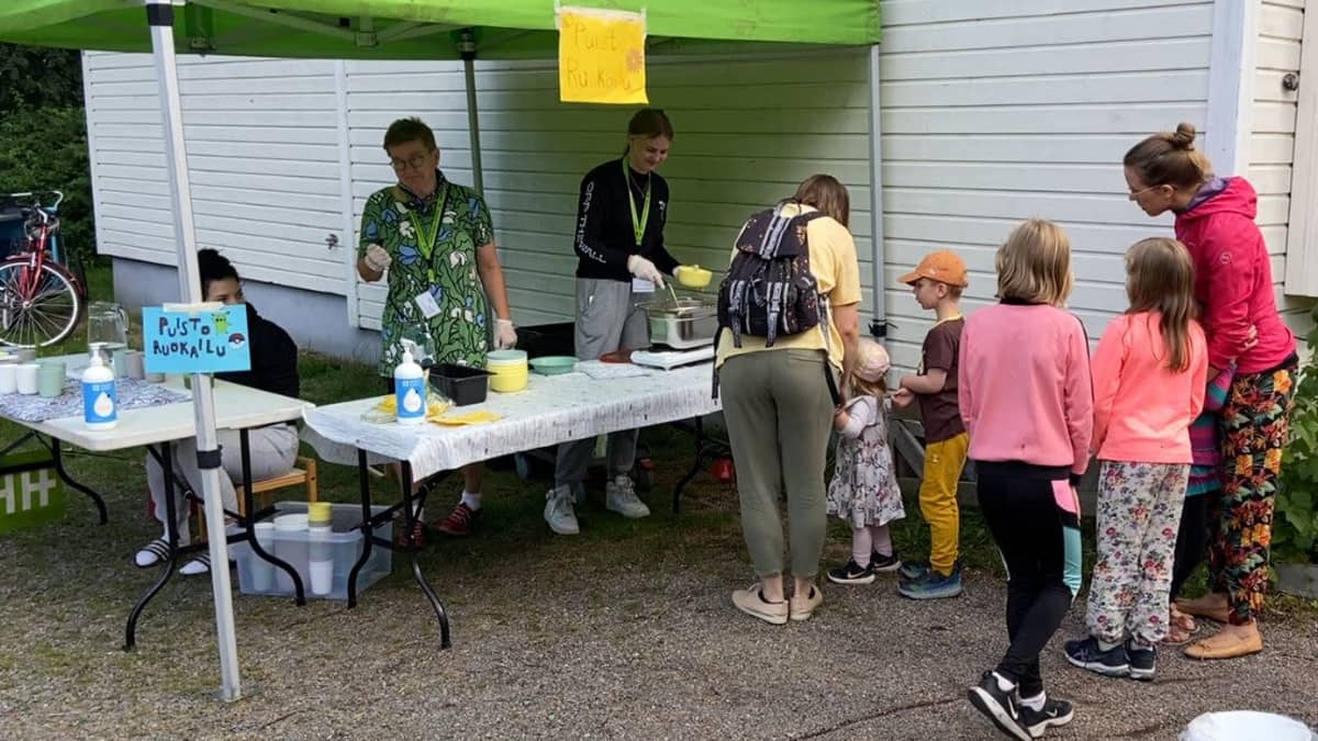 Lapsiperheitä jonottamassa keittolounasta Hämeenlinnan Linnanpuistossa järjestetyssä puistoruokailussa heinäkuussa 2022.