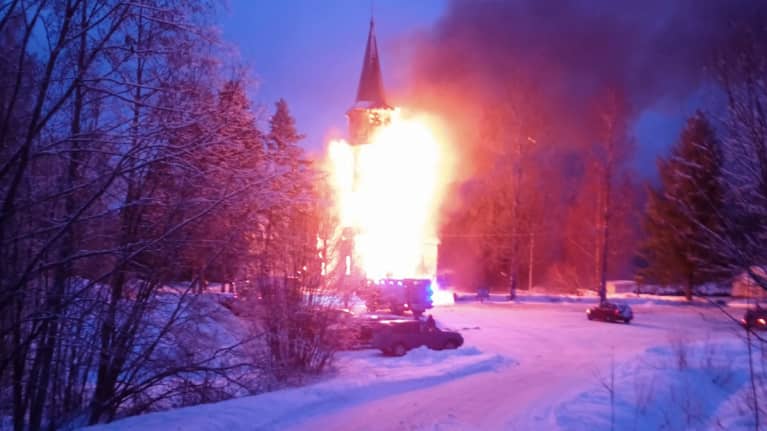 Rautjärven puurakenteinen kirkko tulessa.