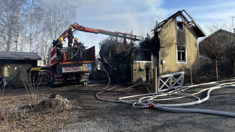Tulipalossa tuhoutunut pieni puinen omakotitalo, pelastuslaitos suorittaa jälikraivausta.