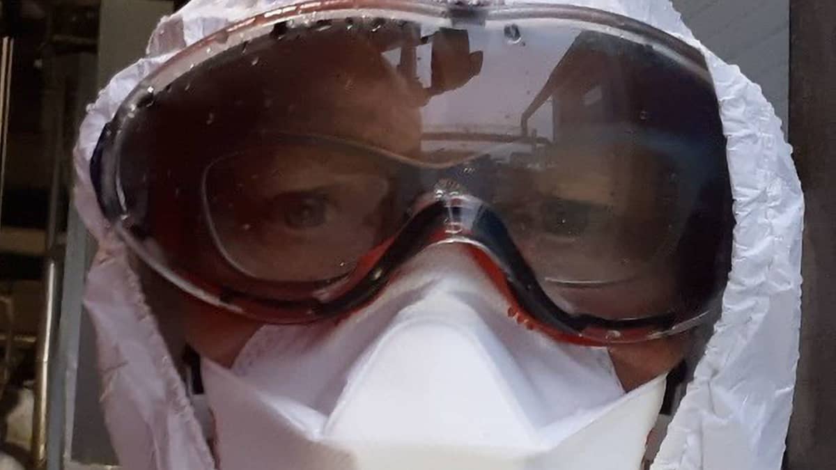 Ihminen katsoo kameraan suojavarusteissa