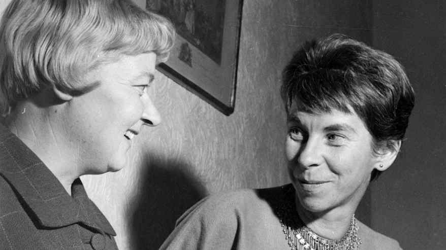 Mustavalkoinen vanha valokuva, jossa kaksi lyhythiuksista henkilöä hymyilee ja katsoo toisiaan silmiin.