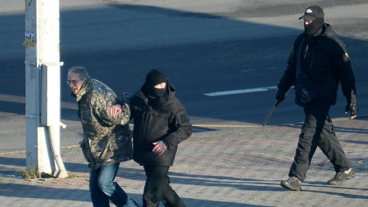 Poliisi ottaa kiinni mielenosoittajaa.