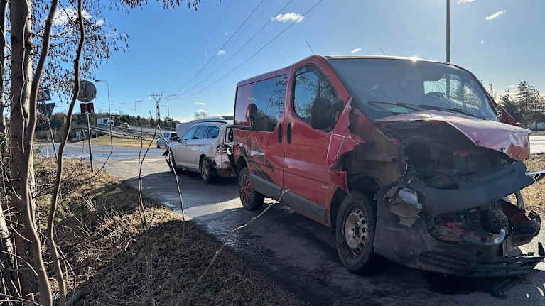 Two vehicles damaged in a crash, a red van in front with a white estate wagon behind it.