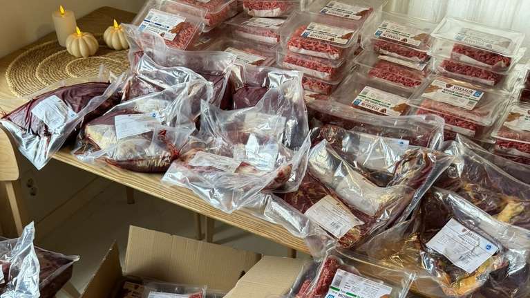Flera bord, golvytor och kartonger är fyllda med vakuumförpackat kött och förpackningar med etiketter.
