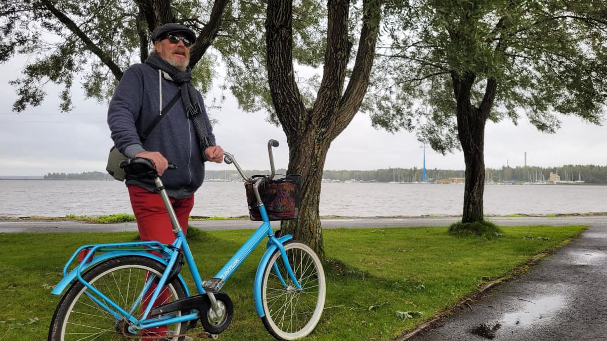 Mies seisoo polkupyöränsä kanssa rannan läheisessä puistossa Vaasassa
