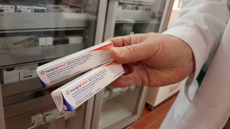 Käsi pitelee influenssarokotteita.