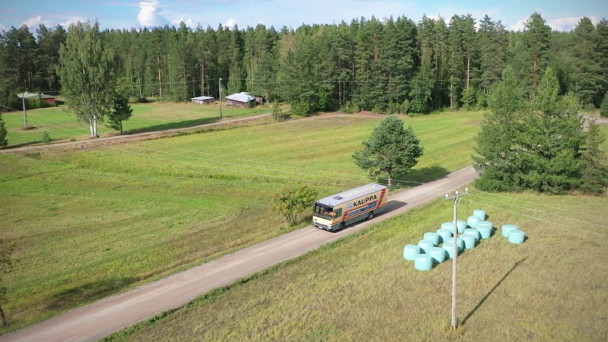 Kauppa-auto ajaa tietä peltojen keskellä aurinkoisena loppukesän päivänä.