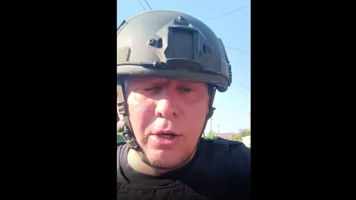 Kuvakaappaus videolta, jossa sotilaskypäräinen mies puhuu kameralle.