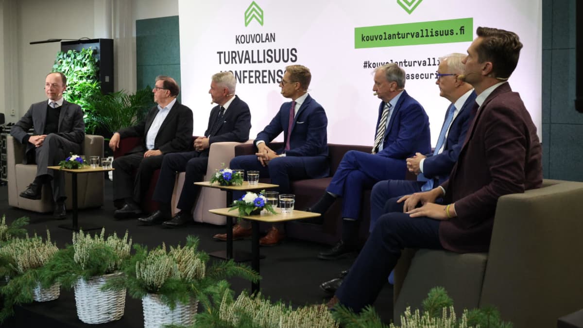 Seitsemän presidenttiehdokasta istuu tenttilavalla.