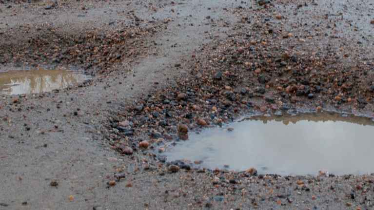 Tjälhål i en sandväg.