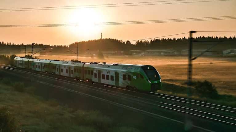 Havainnekuva VR:n uudesta lähijunasta, joka kuvassa ajaa maaseutumaisemassa.