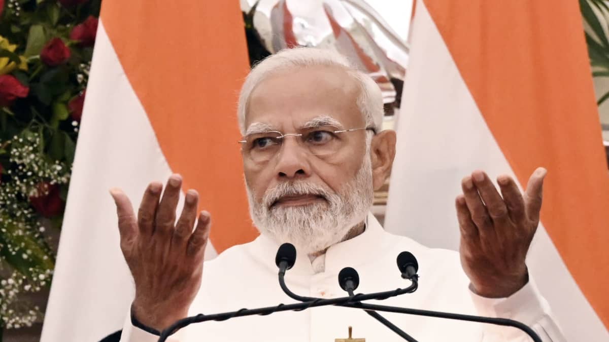Intian pääministeri Narendra Modi puhuu, taustalla Intian lippu. Tuima ilme, kädet ojennettu kämmenet ylöspäin. 