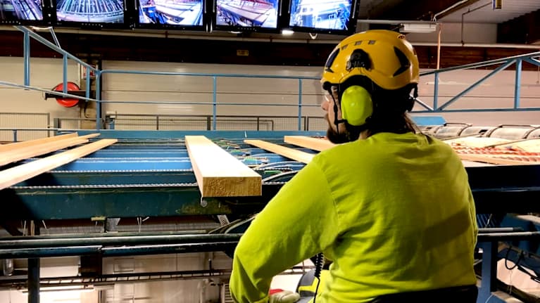 Man i skyddskläder sitter vid en produktionslinje.