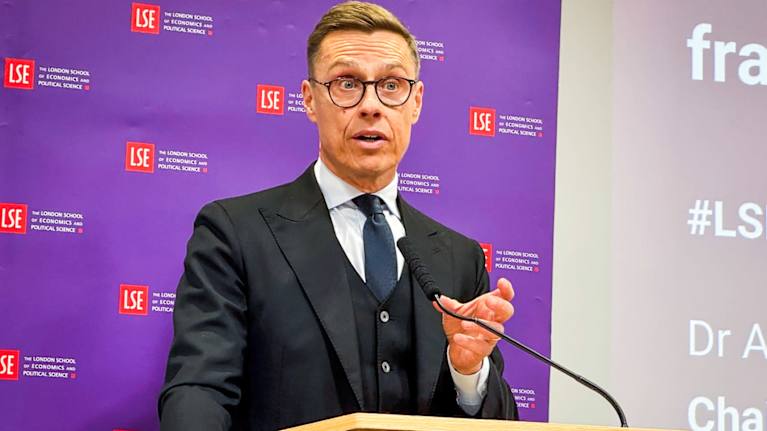 Presidentti Alexander Stubb puhujakorokkeella. Taustalla seinä, jossa London School of Economicsin logoja.