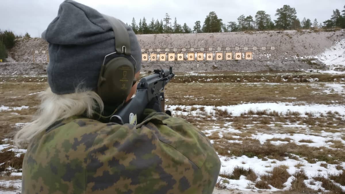 Nainen tähtää kiväärillä ammuntataulua. 