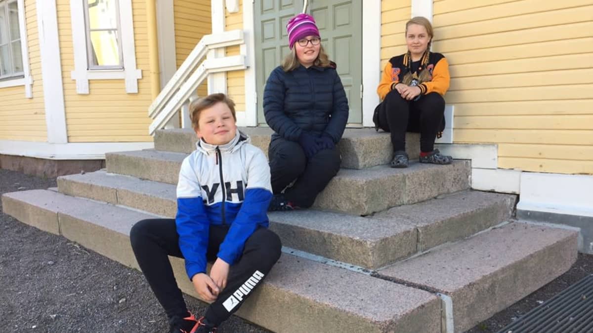 Lappeenrannan Lönnrotin koulun 6.-luokkalaiset Julius, Aino ja Liia istuvat ulkoportailla.