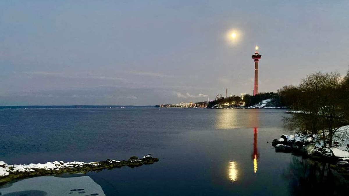 Rannasta jäätynyt Näsijärvi aamuhämärässä. Kauempana loistaa kuutamo, jonka vieressä seisoo Näsinneula.