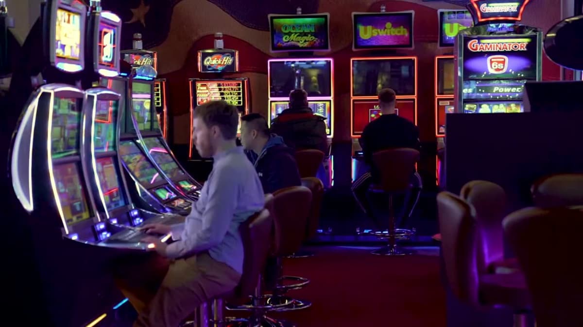 Neljä miestä pelaa pelikoneilla kasinolla. 