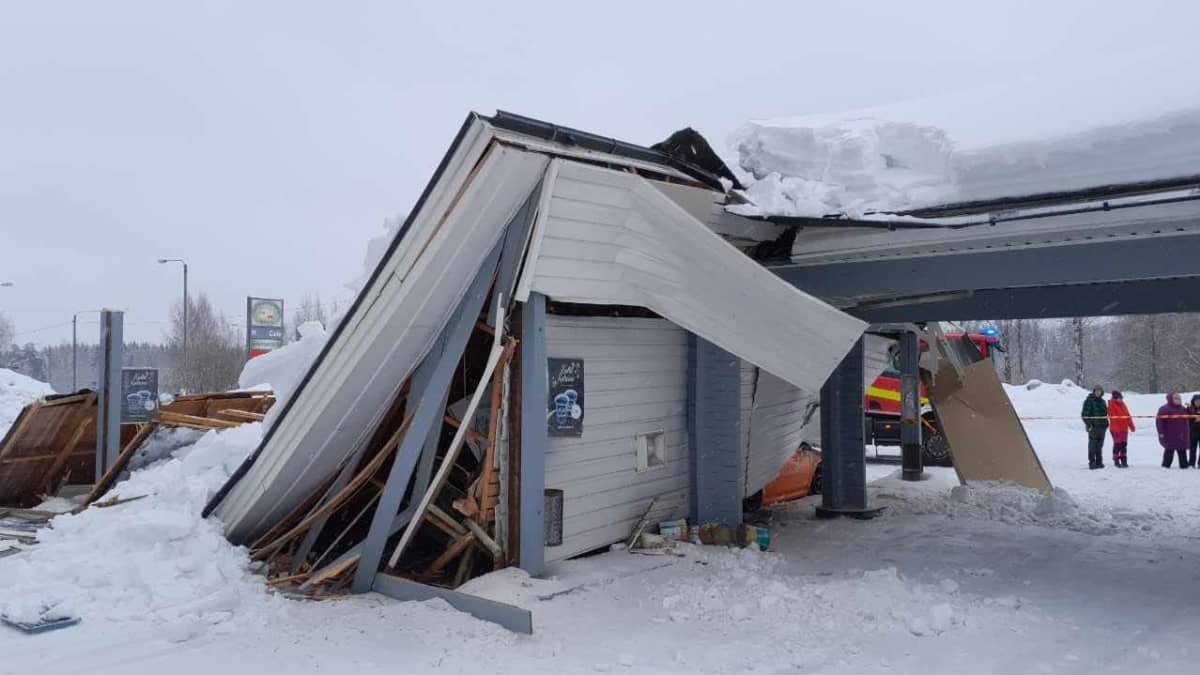 Rakennuksen katto sortunut lumen painosta. Taustalla ihmisiä ja pelastuslaitoksen ajoneuvo.