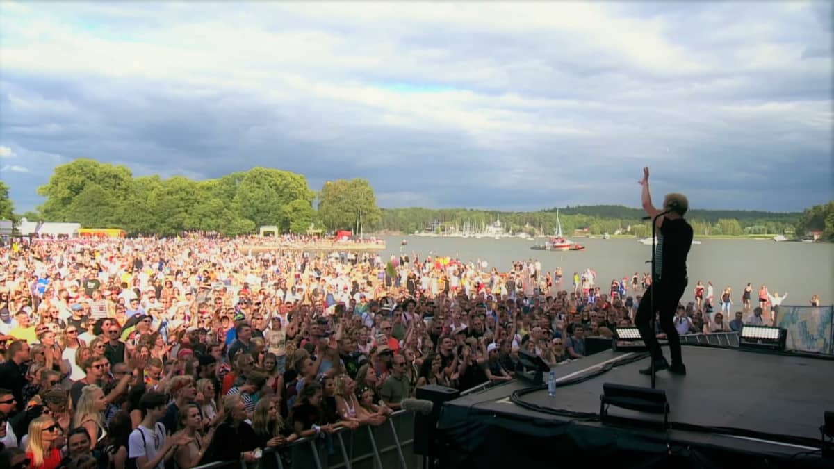 Ismo Alanco performing on stage in front of a huge crowd on the beach at Ruisrock 2019.