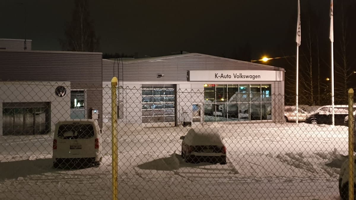 Hämeenlinnalaisen autokaupan K-Auton piha on lähikuvassa. Lumihanki, pihalla muutama auto. Liike on suljettu, koska ilta.