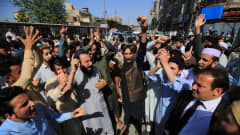 Pakistanilaisia mielenosoittajia kädet ilmassa kadulla, taustalla rakennuksia.