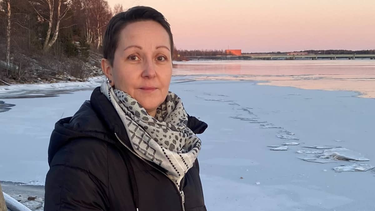 Jonna Pakisjärvi katsoo kameraan osin jäätyneen Kemijoen rannalla punertavan auringonlaskun aikaan..