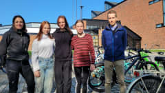Mies ja nainen sekä kolme 7-luokkalaista vaasalaistyttöä seisoo Vaasalaisen Variskan yhtenäiskoulun pihalla ja katsoo kameraan