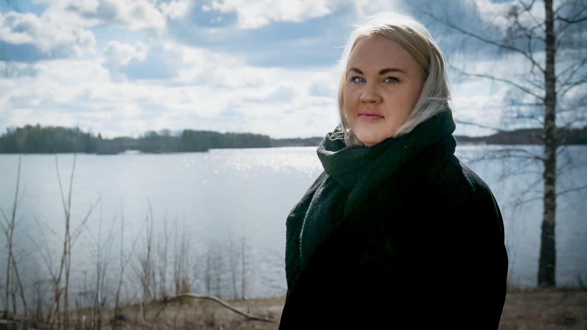 Tanja Heikka katsoo Näsijärven rannassa kameraan ja hymyilee.