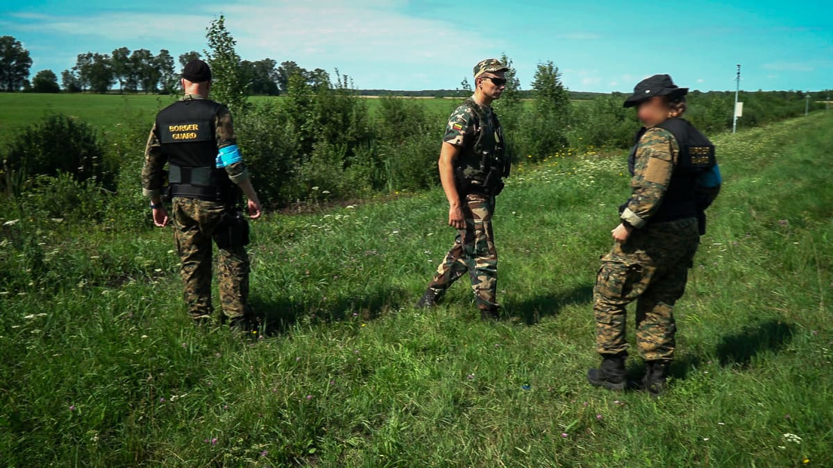 Liettualainen rajavartija opastaa suomalaisia. Tässä kohtaa Liettuan ja Valko-Venäjän erottaa vain kapea oja.