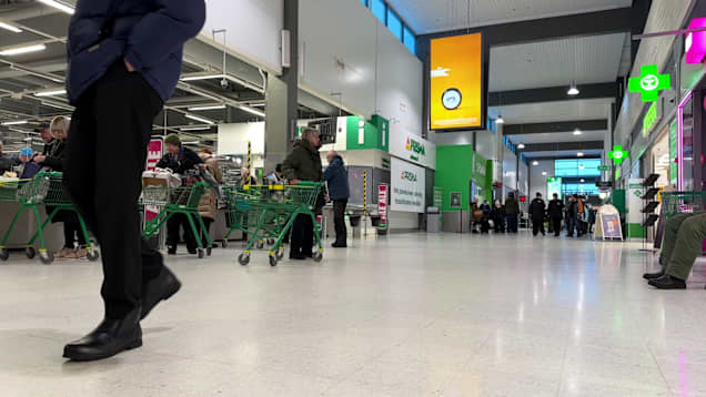 Legs of a man walking past the checkout lines next to a Prisma hypermarket.