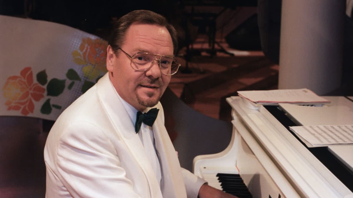 Kapellimestari Risto Hiltunen istuu pianon ääressä valkoinen smokkitakki yllään.