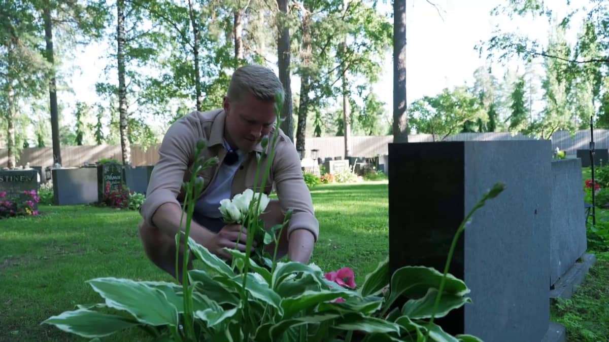 Lassi Tuovi asettelee kukkia Mika Turusen hautakiven äärelle.
