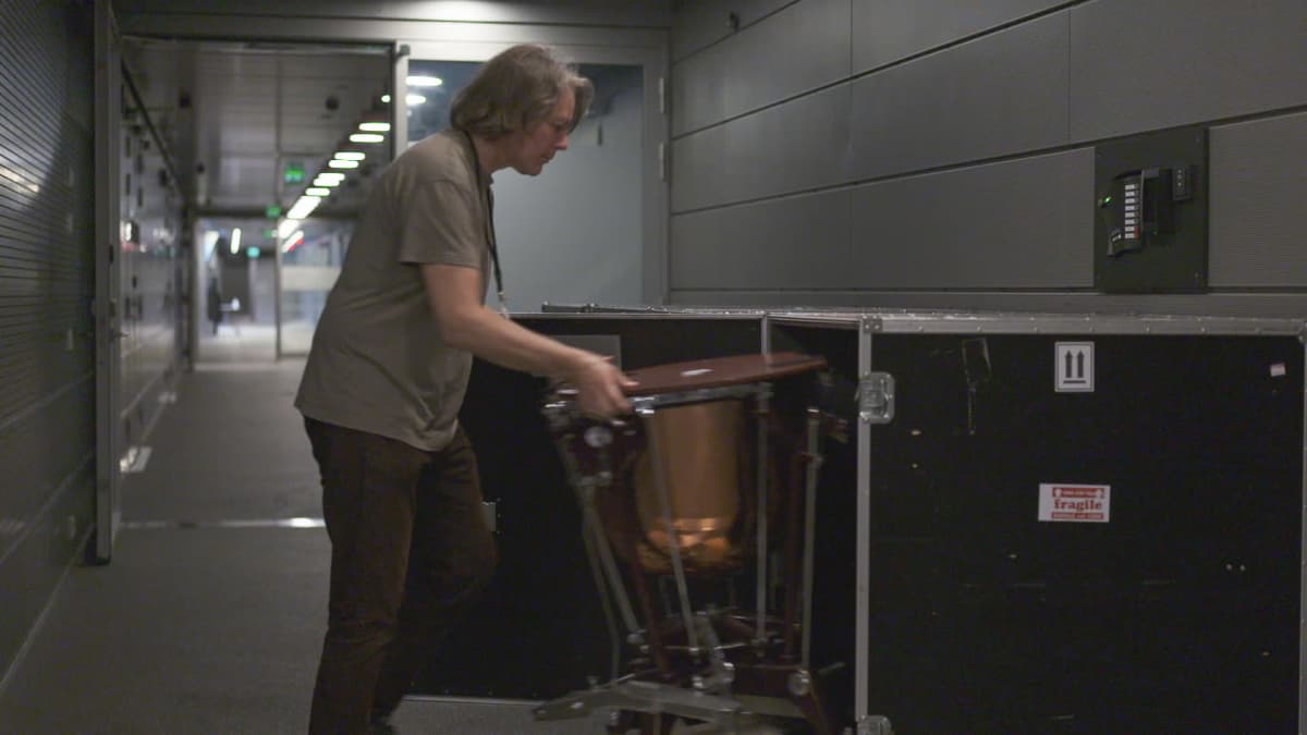Radion sinfoniaorkesterin orkesterijärjestäjä Mikael Tiittanen pakkaa pientä patarumpua kuljetuslaatikkoon Musiikkitalon käytävällä. 