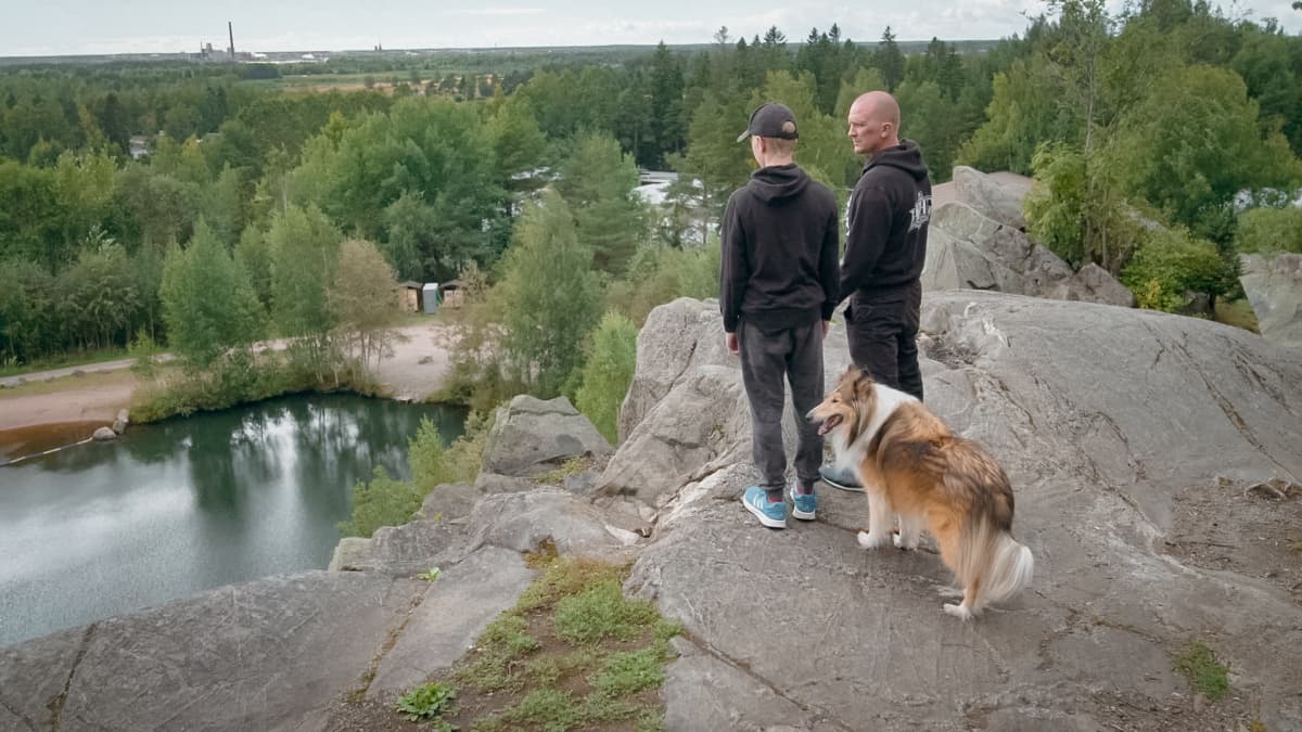 Kai Mattila seisoo kielekkeellä koiran kanssa ja katselee maisemaa.