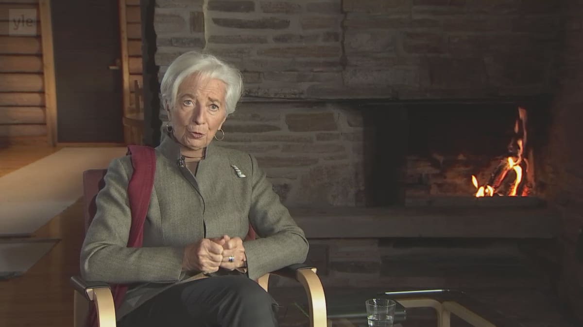 Christine Lagarde i en fåtölj framför en brasa.