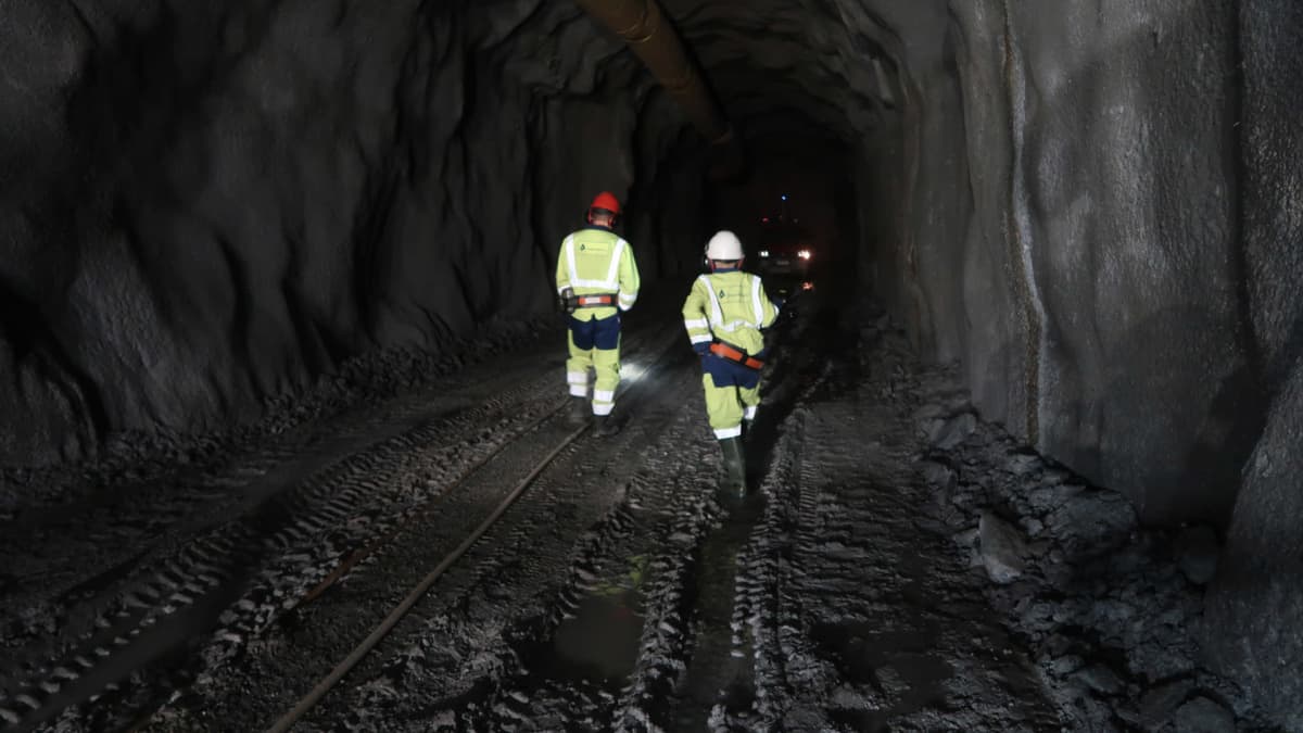 Kaivosmiehiä kävelemässä pimeähkössä kaivostunnelissa Oriveden kultakaivoksessa.