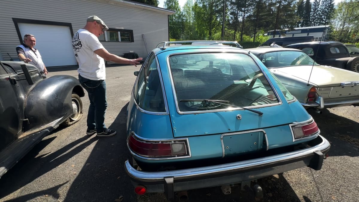 Lippalakkipäinen mies tutkii AMC Pacer merkkistä autoa.