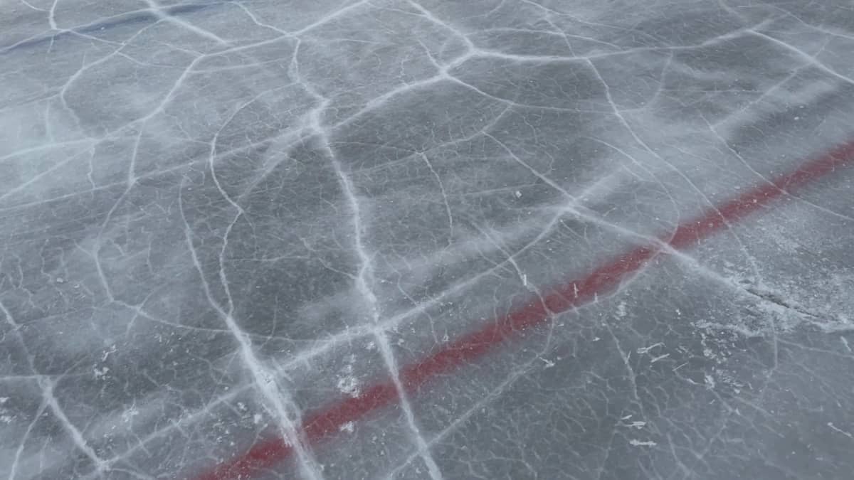 Lähikuva Porin tekojääradan pinnasta, jossa näkyy punainen viiva ja railottunutta jäätä