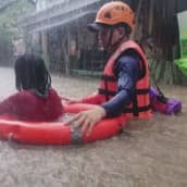 Pelastustyöntekijä auttaa naista tulvan keskellä Filippiineillä.