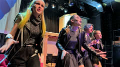 Neljä nuorta näyttelijää laulaa teatterilavalla.