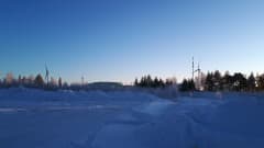 Tuulimyllyjä ja öljysatama lumisessa maisemassa.