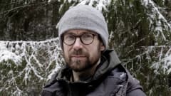 Mies lumisessa metsässä.